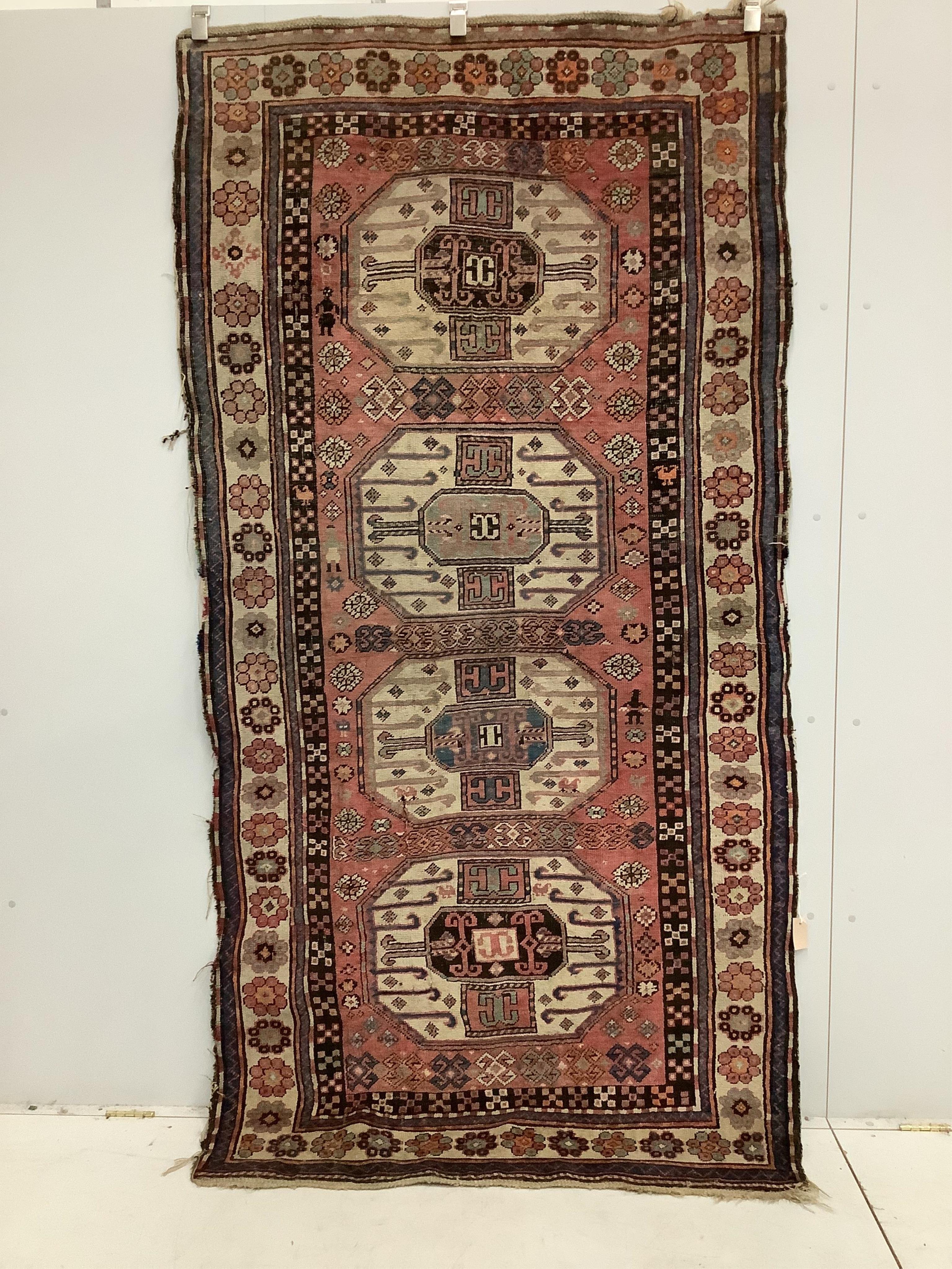 A Caucasian red ground rug, 265 x 130cm. Condition - faded with some wear at the margins